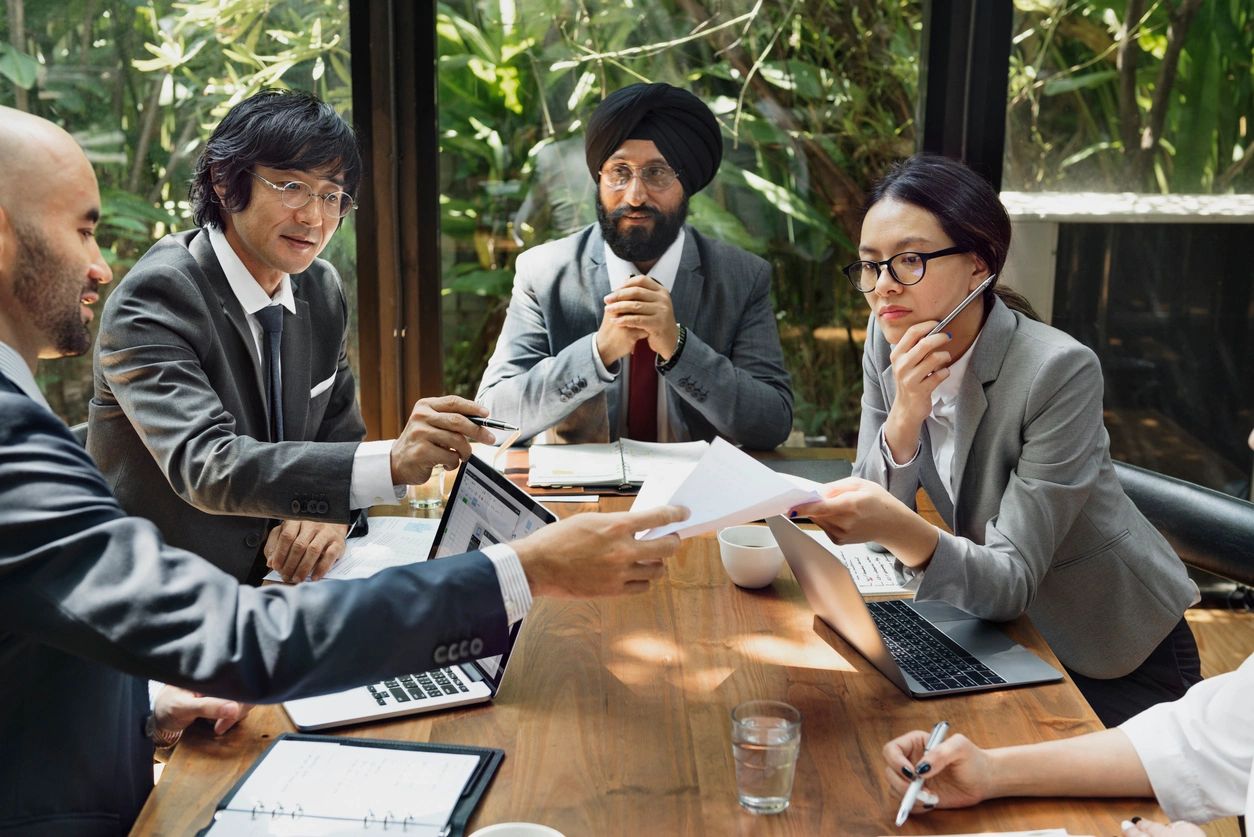 Multinational professionals discussing merger and acquisition strategies during a meeting.