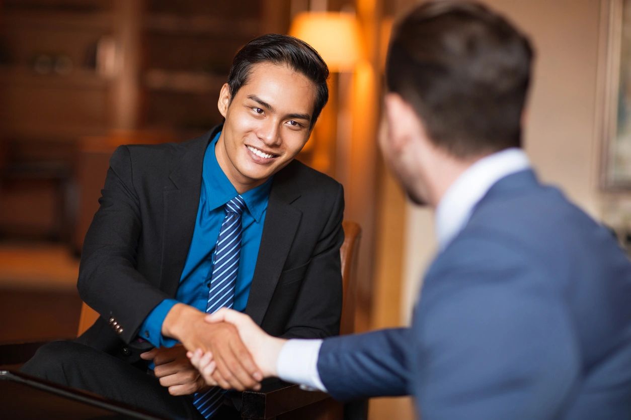 Two businessmen shaking hands to finalize an asset purchase agreement.